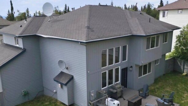 Una casa de dos pisos con terraza, antena parabólica y zona de estar al aire libre.