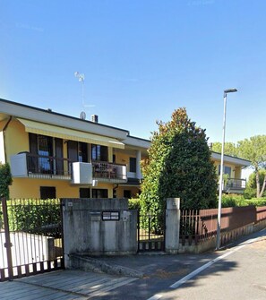 En bostadsbyggnad med en grind vid entrén, en balkong och en satellitantenn.