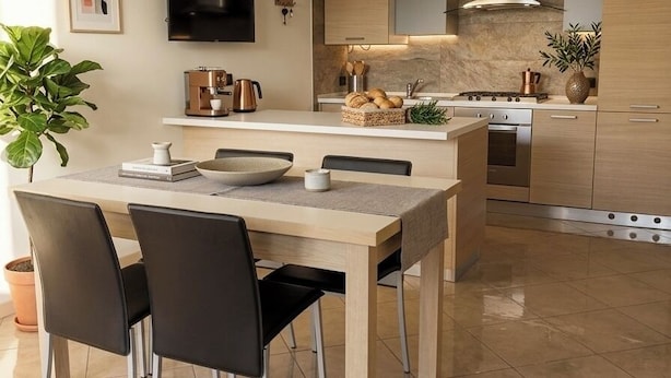 A modern kitchen with a dining area, featuring a flat-screen TV, a coffee machine, and a large island with seating. - Welcome to our vacation home, "Azzurro Garda🩵," in Sirmione! (Sirmione)