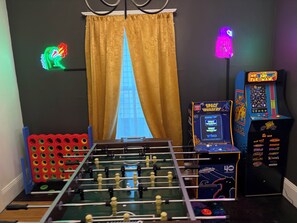 A room with a foosball table, two arcade games, and a window with curtains. - Fun Eclectic Designer Home in Historic Strathmore (Syracuse)