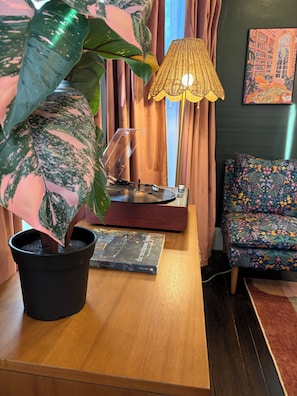 Une table en bois, sur laquelle se trouvent un pot de fleurs, une lampe, un livre et une chaise.