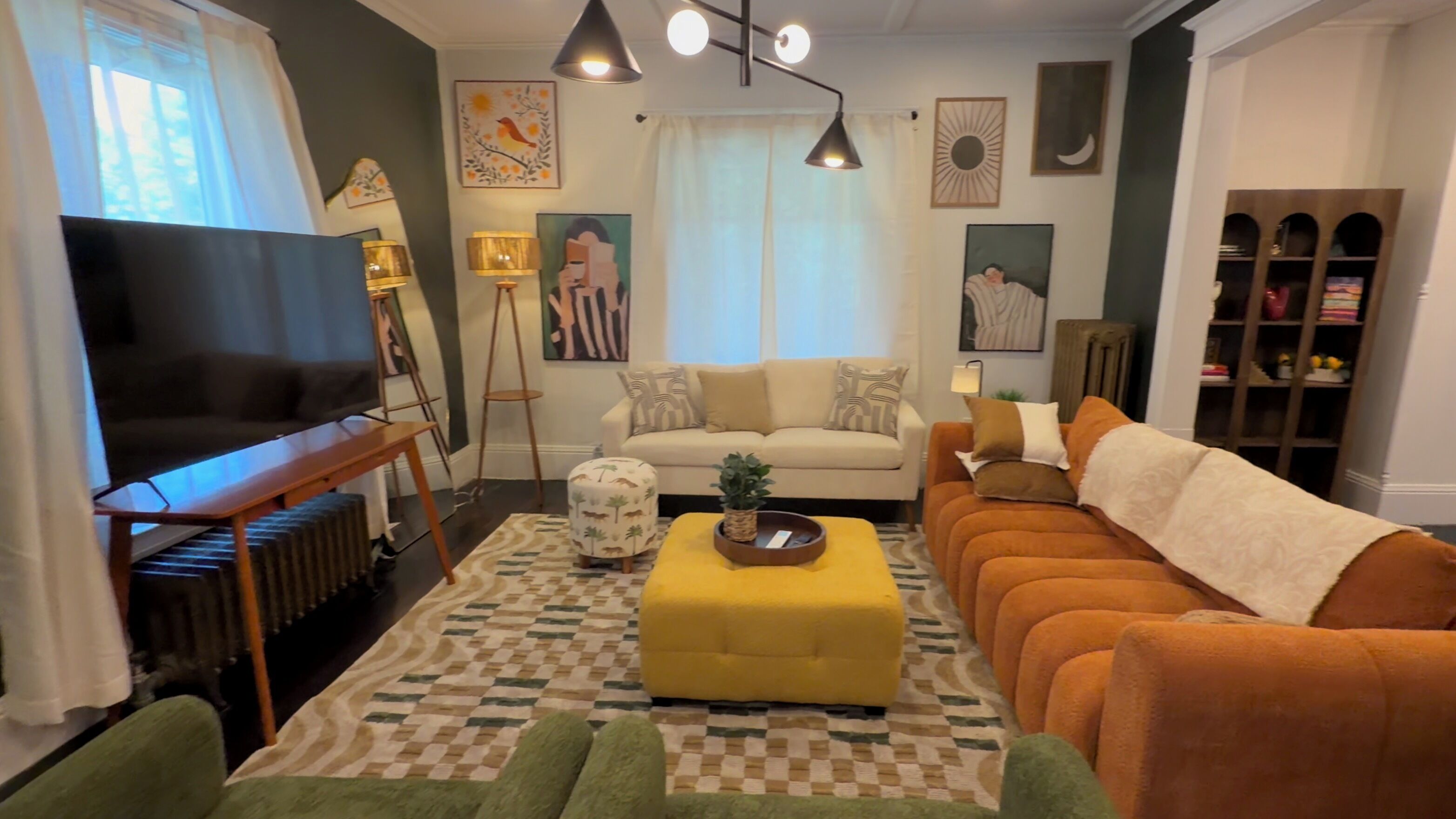Een woonkamer met een bank, poef en een televisie.