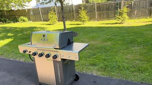 Een draagbare gasgrill met een extra brander en een bedieningspaneel met vier knoppen.