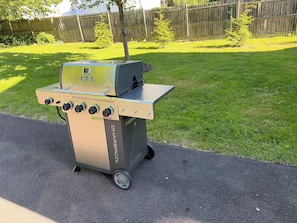 A portable gas grill with a side burner and a control panel with four knobs. - Fun Eclectic Designer Home in Historic Strathmore (Syracuse)