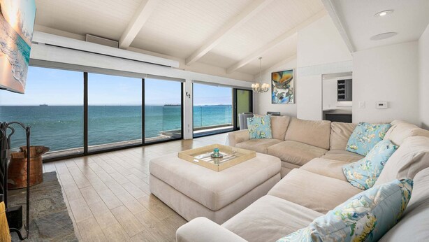 Een ruime woonkamer met een groot raam met uitzicht op de zee, een moderne bank en een minimalistisch design.