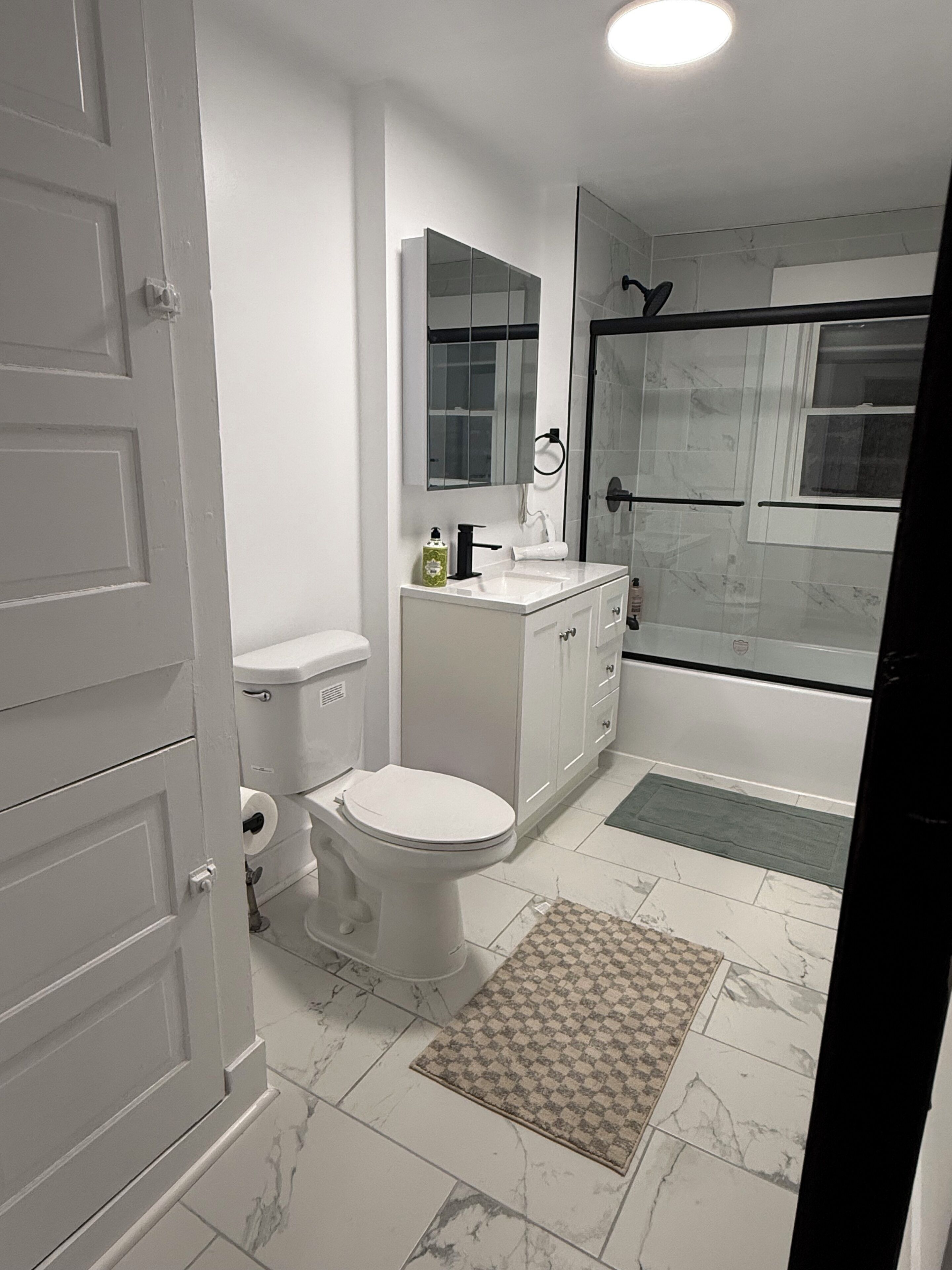 A bathroom with a toilet, sink, mirror, and shower area.