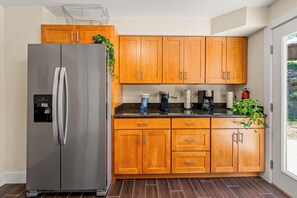 A modern kitchen with wooden cabinets, a stainless steel refrigerator, and a coffee maker. - Private 4BR • Free Parking • Near Airport & Seattle (Tukwila)