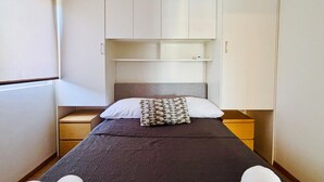 A narrow hotel room with a single bed, a nightstand, a small shelf, and a wardrobe. - Stunning apartment in Stinjan (Stinjan)