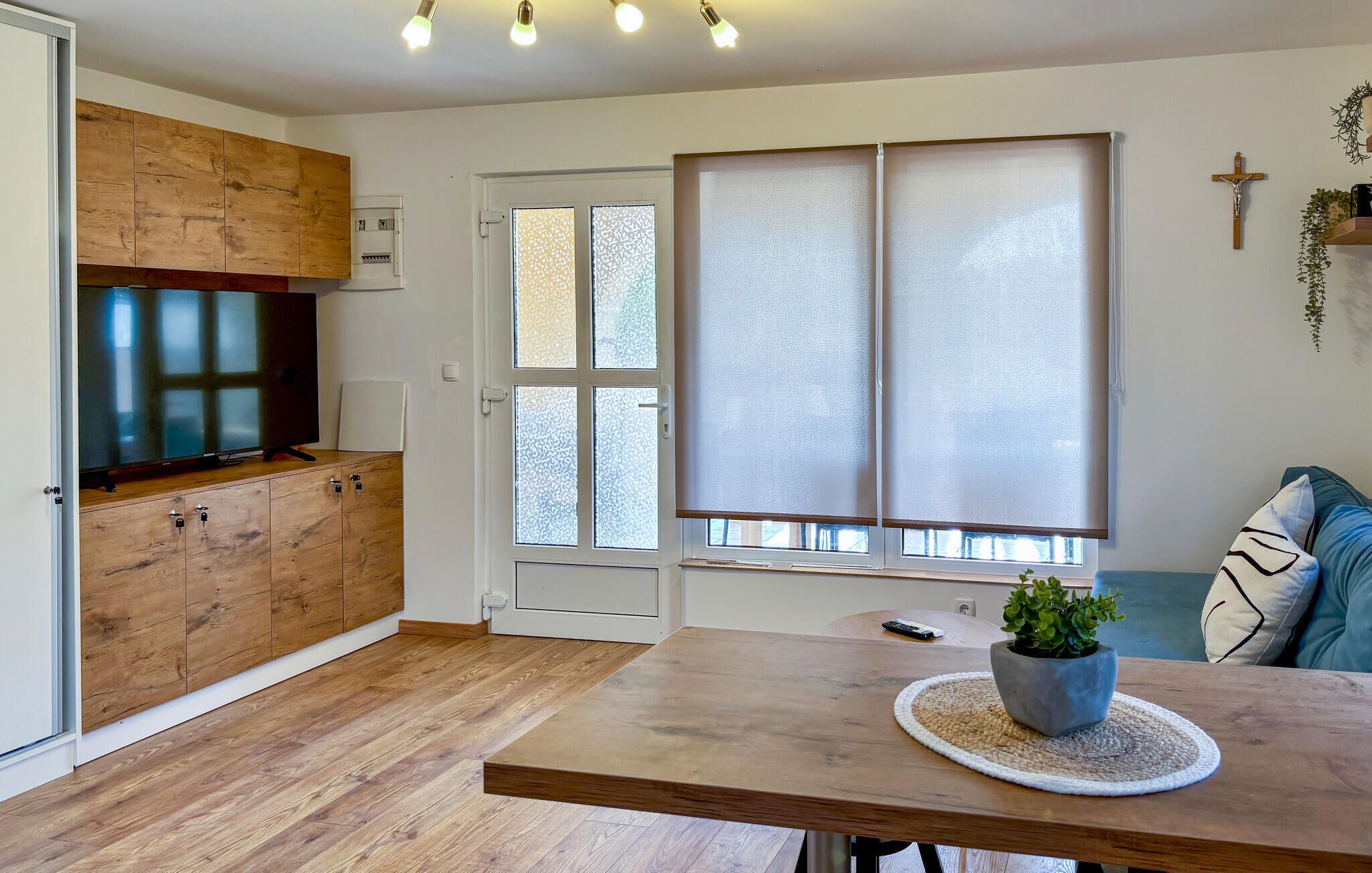 Een moderne keuken met houten kastjes, een ingebouwde televisie en een eethoek met een tafel en stoelen.