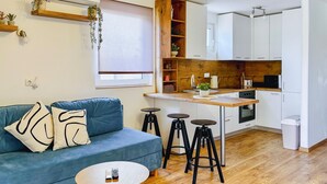 A compact living space with a sofa, a small round table, a kitchen area with a wooden countertop, and a white cabinet. - Stunning apartment in Stinjan (Stinjan)