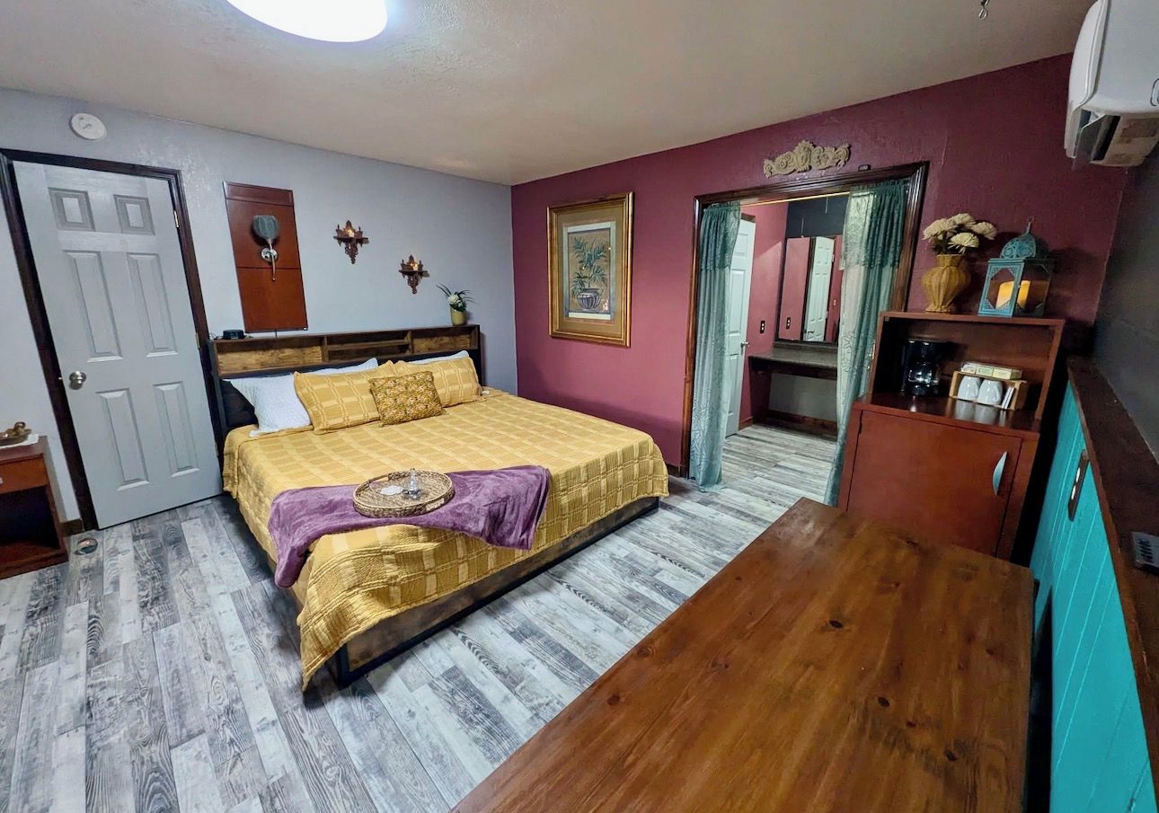 Une chambre à coucher avec un lit, une table en bois, une armoire et une porte.