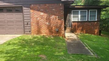 A residential house with a garage, brick exterior, and a small porch.