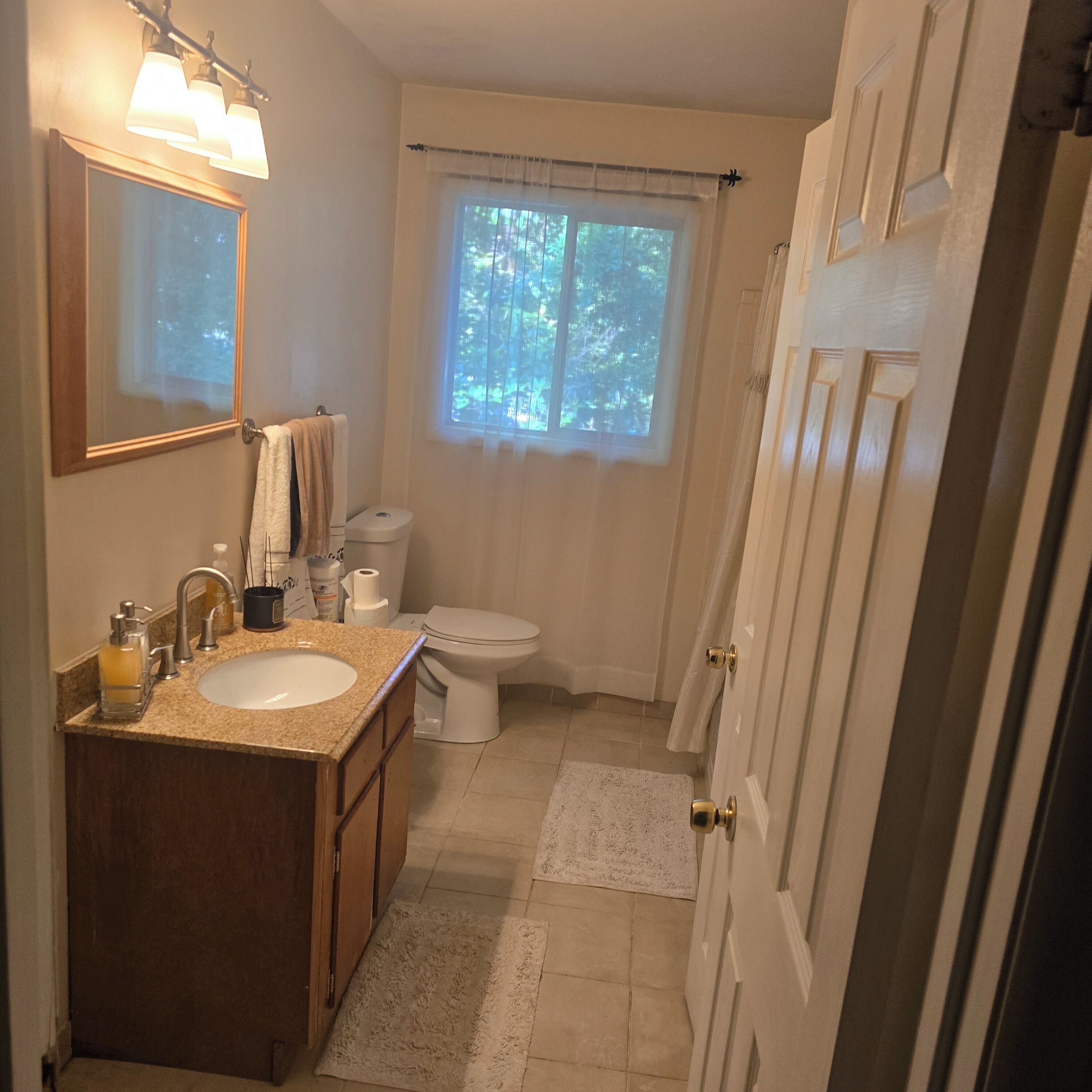 A bathroom with a sink, toilet, and window.