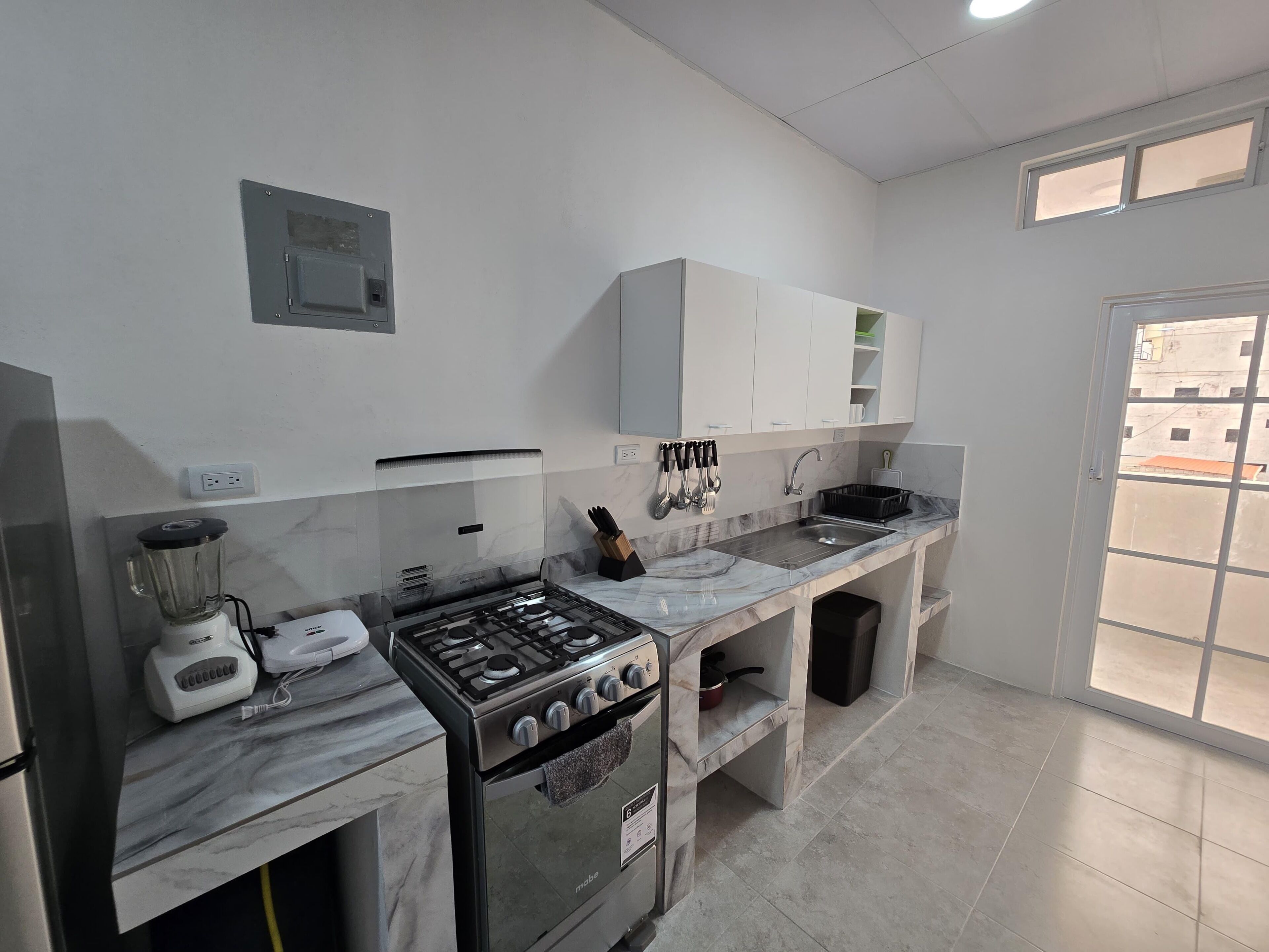 Una cocina moderna con estufa a gas, horno, licuadora y pileta.