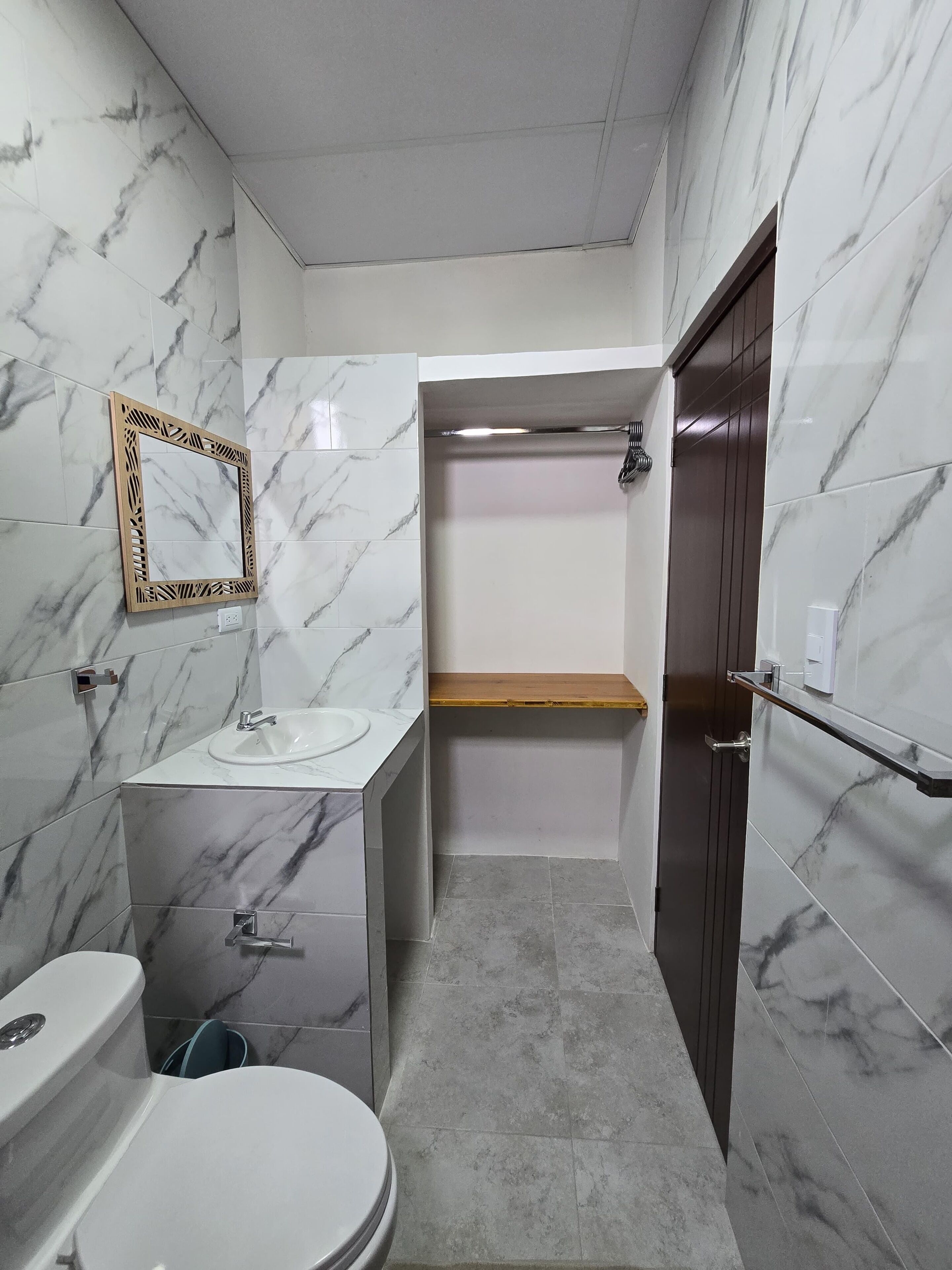 Een badkamer met toilet, wastafel, spiegel en douche.