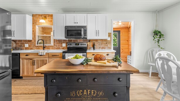 A kitchen with white cabinets, a wooden countertop, a black refrigerator, and a microwave.