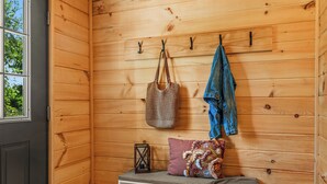 A wooden interior with a bench, storage shelves, a door, and a window.