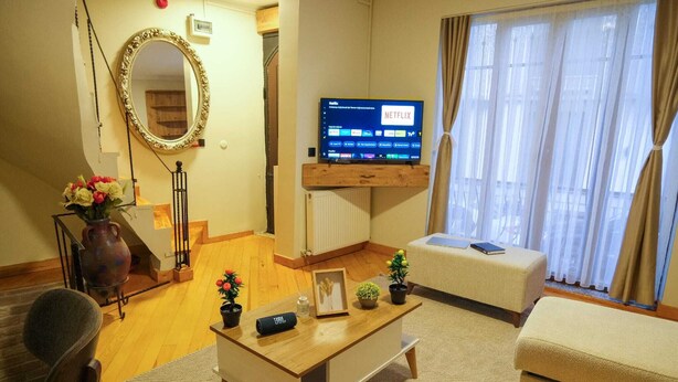Una sala de estar con televisor, sofá, mesa de centro y espejo.