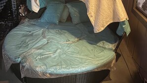 Una cama con cabecera curvada, una ventana que ofrece vistas del cielo nocturno y una lámpara colgante arriba.