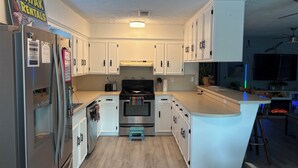Una cocina moderna con armarios blancos, electrodomésticos de acero inoxidable y una isla central.