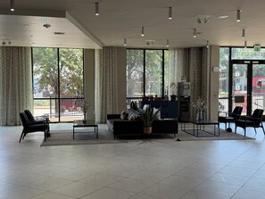 A spacious lobby with a seating area, a reception desk, and large windows offering a view of the outside. - Cozy 1-bedroom apartment with AC in peaceful Houston (Houston)