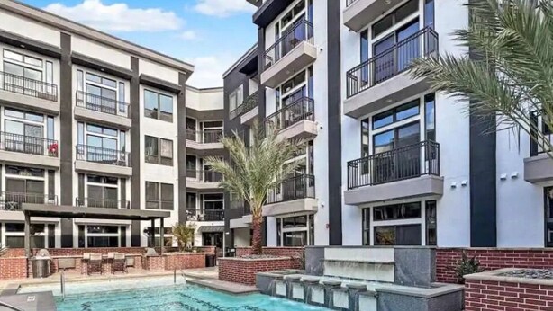 A modern apartment building with a swimming pool, outdoor seating, and a palm tree. - Cozy 1-bedroom apartment with AC in peaceful Houston (Houston)