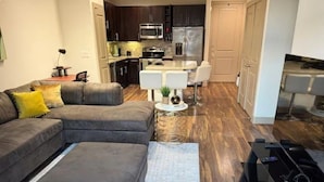 A modern living room with a sectional sofa, a small coffee table, and a TV stand. - Cozy 1-bedroom apartment with AC in peaceful Houston (Houston)