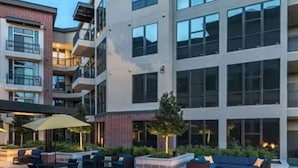 A multi-story building with outdoor seating areas, a fire feature, and a brick facade. - Cozy 1-bedroom apartment with AC in peaceful Houston (Houston)