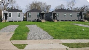 Three single-story houses with front porches, a well-maintained lawn, and a gravel driveway. - Modern2Bed2Bath Oasis 3 mins to LSUlFreeParking (Baton Rouge)