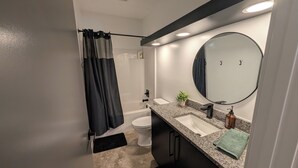 A modern bathroom with a toilet, sink, and shower. - Dune Haus + Indiana National Dunes Park (Portage)
