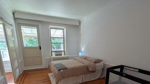 A bedroom with a bed, a desk, and a window.