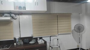 A kitchenette with a stove, sink, and cabinets, a fan, and a window with blinds. - 2-BR w/ Full Kitchen & AC near Farmer’s Market, Araneta Coliseum & Greenhills (Quezon City)