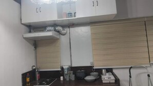 A kitchen with white cabinets, a gas stove, and a stainless steel kettle. - 2-BR w/ Full Kitchen & AC near Farmer’s Market, Araneta Coliseum & Greenhills (Quezon City)