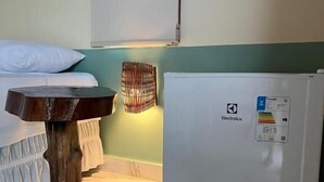 A room with a bed, a small wooden table, and a white refrigerator. - Green Village  (Barreirinhas)