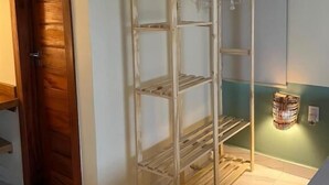 A room with a wooden door, a metal shelving unit, and a wall-mounted light fixture. - Green Village  (Barreirinhas)