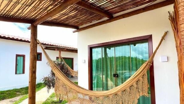 A covered outdoor area with a hammock, wooden flooring, and a glass door. - Green Village  (Barreirinhas)