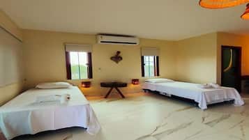 Habitación de hotel con dos camas individuales, una mesita pequeña, un equipo de aire acondicionado y una ventana con vistas.