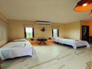 Habitación de hotel con dos camas individuales, una mesita pequeña, un equipo de aire acondicionado y una ventana con vistas.