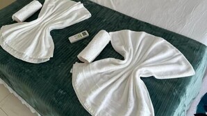 A bed with white linens, a green bedspread, and two neatly folded white towels. - Green Village  (Barreirinhas)