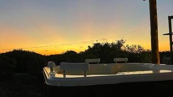 A rooftop terrace with a thatched roof, a table, and chairs.