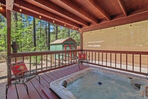 A hot tub on a wooden deck with a view of a forest.
