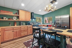 Una cocina con armarios de madera, un refrigerador de acero inoxidable y un comedor con sillas y una mesa.