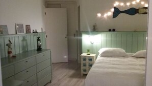 Et soveværelse med seng, kommode, natbord og billeder p å væggen.