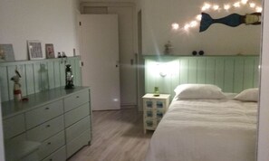 Ein Schlafzimmer mit Bett, Kommode, Nachttisch und Wandgestaltungen.