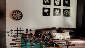 Ein Fußballtisch, eine Dartscheibe und verschiedene Wanddekorationen, darunter Superhelden-Symbole.