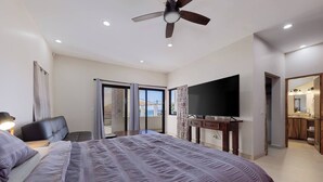 Une chambre à coucher avec un lit, une télévision, un ventilateur de plafond et un balcon avec vue.