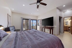 Ein Schlafzimmer mit Bett, Fernseher, Deckenventilator und einem Balkon mit Blick.