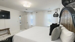 Een slaapkamer met een groot bed, een aan de muur bevestigde televisie en een houten hoofdeinde.