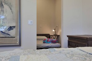 Un dormitorio con cama, mesita de noche, lámpara, cómoda y un cuadro en la pared.
