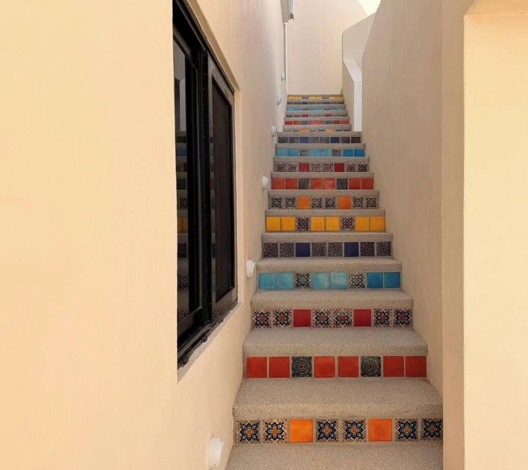 A staircase with colorful tiles leading to a door.
